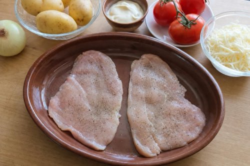 Baked chicken breasts with potatoes, tomato and cheese